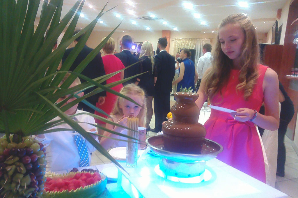 Goście weselni przy fontannie z czekoladą